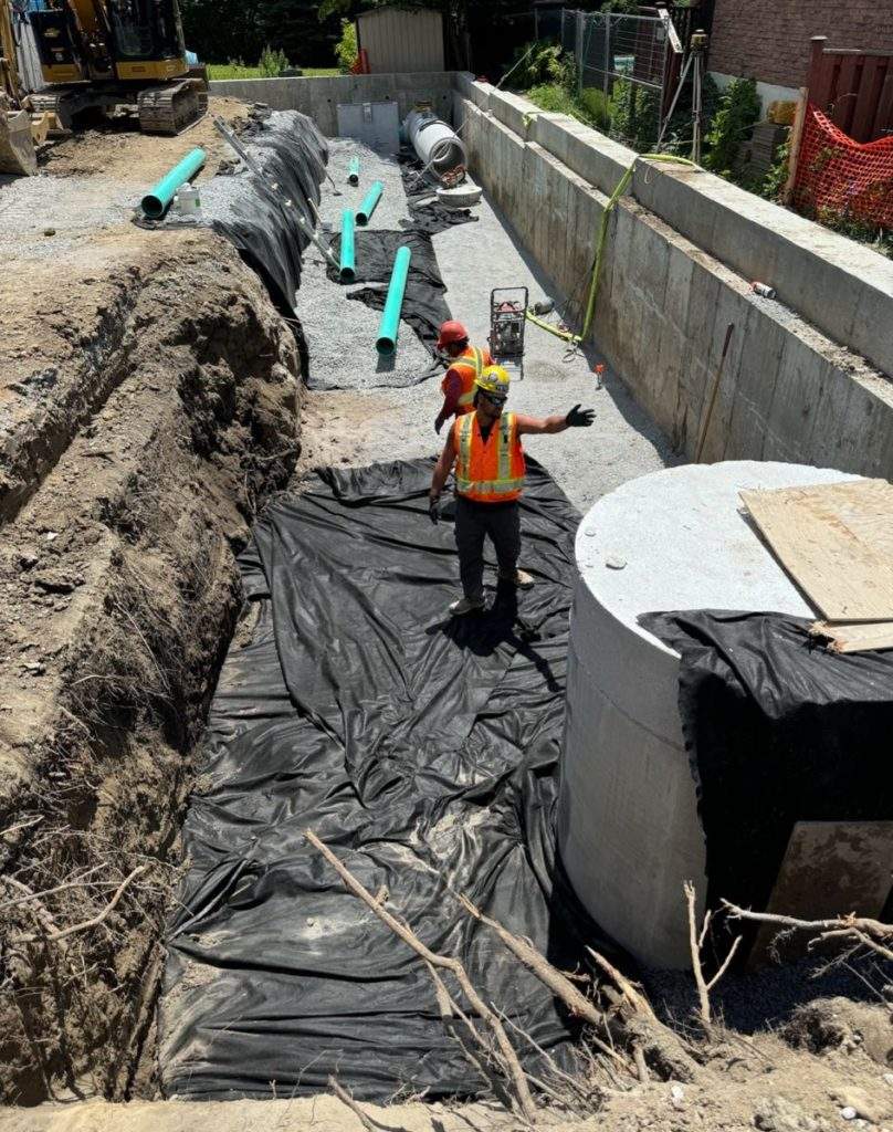 Wallace Excavation team working on underground infrastructure, installing sewer and water mains for new developments, ensuring proper backfill and road reconstruction.