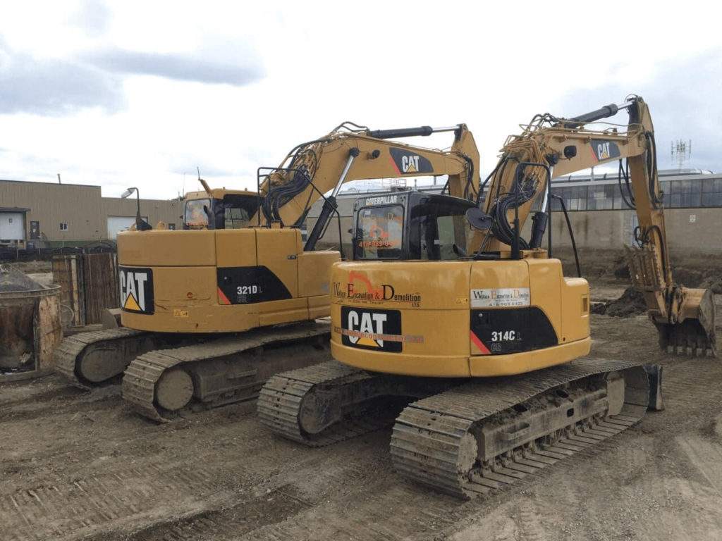 Heavy construction equipment parked on a job site, surrounded by materials and debris, representing excavation and demolition services in the GTA.