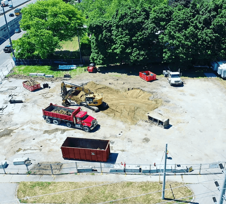 Excavator at work on a construction site, surrounded by dirt and construction materials, illustrating excavation and demolition services in the GTA.