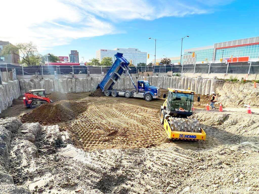 Backfilling process being carried out by the Wallace Excavation team, using soil and gravel to fill excavated areas around a foundation, ensuring stability and proper drainage.